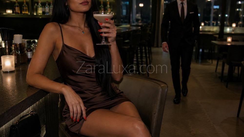 A sexy brunette companion sat at a bar as a gentleman approaches